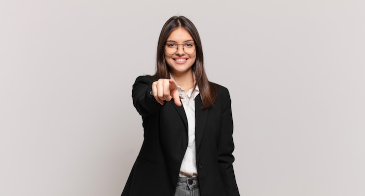 Photo jeune femme d'affaires pointant vers la caméra avec un sourire satisfait, confiant et amical, vous choisissant