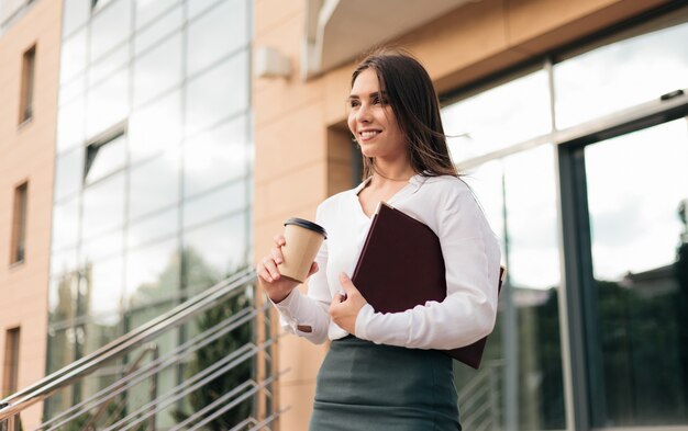 Jeune femme d'affaires professionnelle déterminée portant un chemisier et une jupe quittant le centre d'affaires