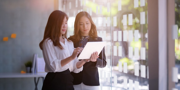 Jeune femme d'affaires professionnelle travaillant ensemble sur leur projet lors de l'utilisation de la tablette