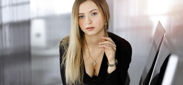 Jeune femme d'affaires prospère dans un cabinet ensoleillé d'une entreprise. Portrait d'entreprise ou portrait d'une secrétaire dans un bureau.