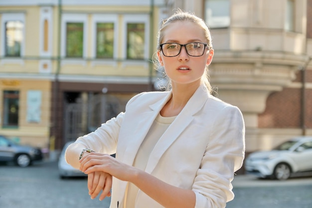 Jeune femme d'affaires prospère en regardant sa montre-bracelet