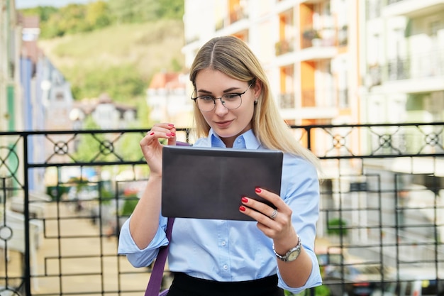 Jeune femme d'affaires prospère avec tablette numérique dans la rue de la ville