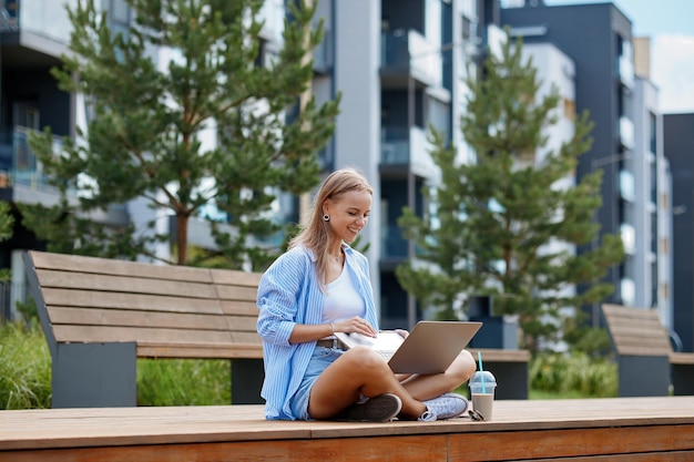 Photo une jeune femme d'affaires prospère en vacances assise avec un ordinateur portable à l'extérieur
