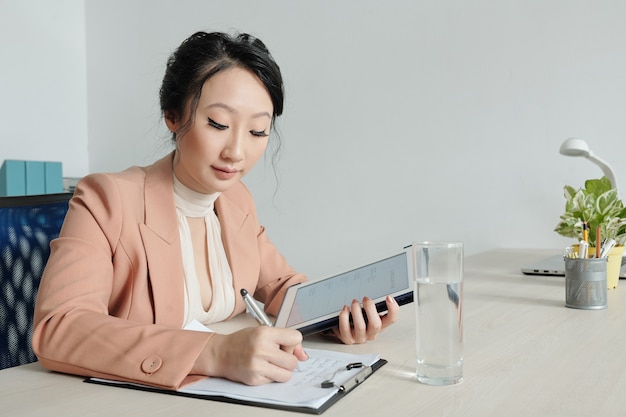 Jeune femme d'affaires remplissant un formulaire de cv et écrivant une lettre de motivation lors de la recherche d'un emploi