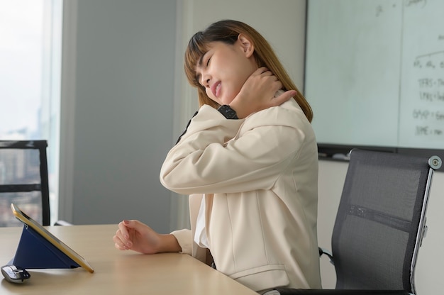 Jeune femme d'affaires ressentant une douleur au cou et au dos dans un bureau moderne