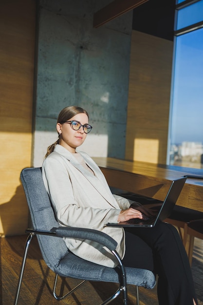 Jeune femme d'affaires réussie dans des verres avec un ordinateur portable au bureau