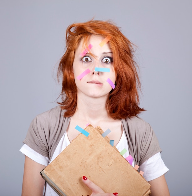 Jeune femme d&#39;affaires rousse avec livre et notes sur le visage.