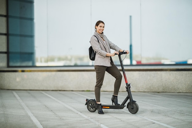 Une jeune femme d'affaires avec un scooter électrique va travailler.