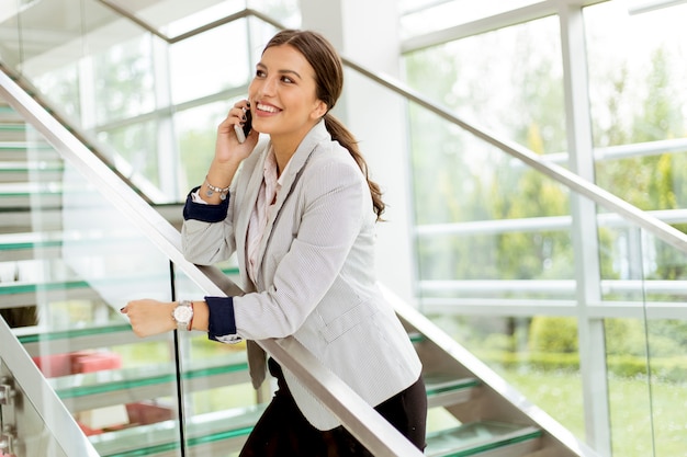 Jeune Femme D'affaires Se Dresse Sur Les Escaliers Au Bureau Et Utilise Un Téléphone Mobile