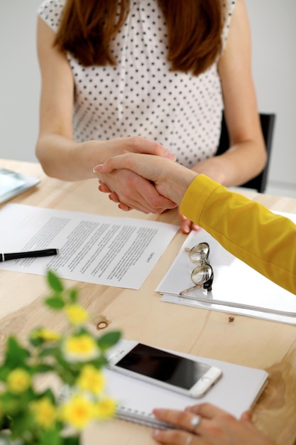 Jeune femme d'affaires se serrant la main après la signature du contrat