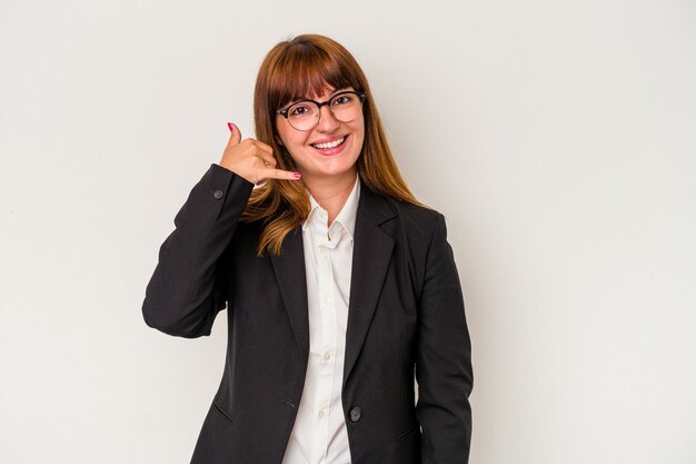 Jeune femme d'affaires sinueuse caucasienne isolée sur fond blanc montrant un geste d'appel de téléphone portable avec les doigts.