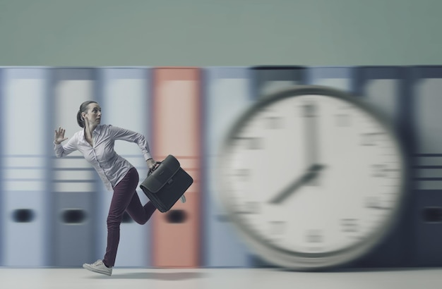 Photo jeune femme d'affaires stressée qui court vite et avec une horloge énorme, elle est en retard pour le travail, la gestion du temps et le concept des délais.