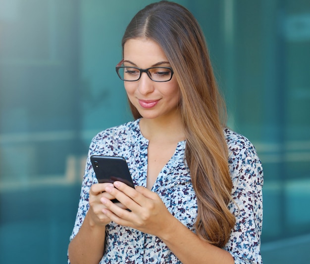 Jeune femme d'affaires tapant sur le smartphone à l'extérieur