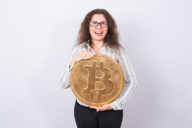 Jeune femme d'affaires tenant un bitcoin doré