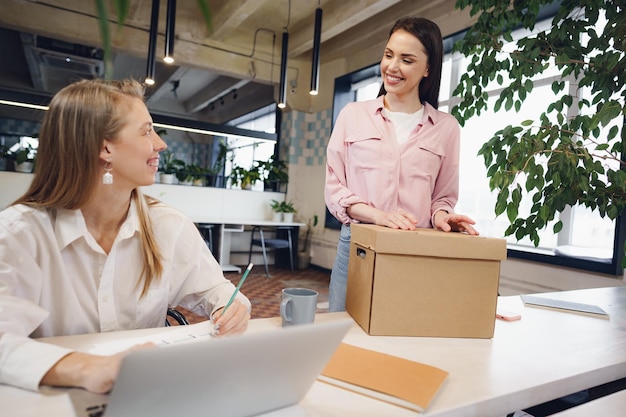 Jeune femme d'affaires tenant une boîte d'effets personnels sur le point de quitter le bureau après avoir quitté son emploi