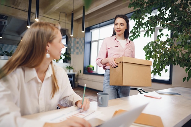 Jeune femme d'affaires tenant une boîte d'effets personnels sur le point de quitter ses fonctions après avoir quitté son emploi