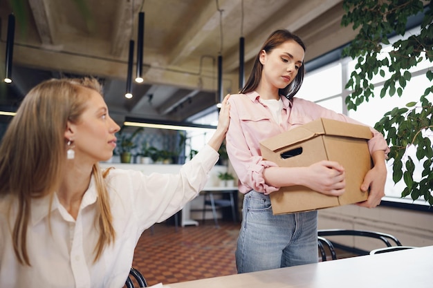 Jeune femme d'affaires tenant une boîte d'effets personnels sur le point de quitter ses fonctions après avoir quitté son emploi