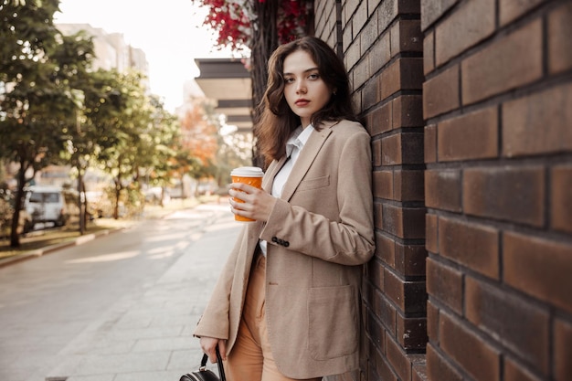 jeune femme d'affaires tenant un café de l'arrière-plan de l'immeuble de bureaux moderne