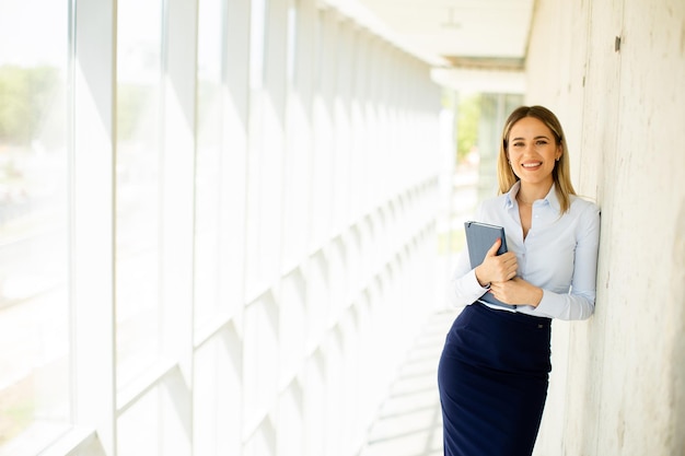 Jeune femme d'affaires tenant avec un ordinateur portable dans le couloir du bureau