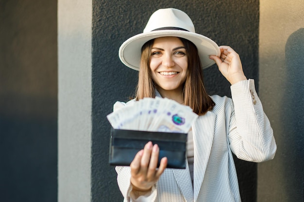 Jeune femme d'affaires tenant un portefeuille noir avec des livres dans les mains gros plan des mains féminines Le concept de paiements en espèces, d'épargne et de salaires