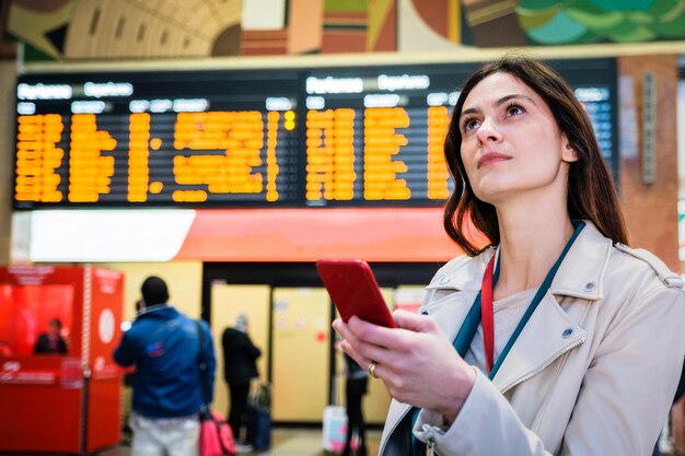 Photo une jeune femme d'affaires tient un smartphone en levant les yeux.