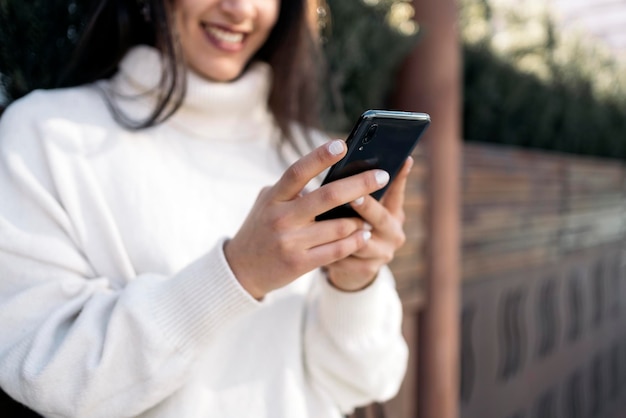 Jeune femme d'affaires en train de taper sur son téléphone Elle sourit et porte des vêtements décontractés intelligents