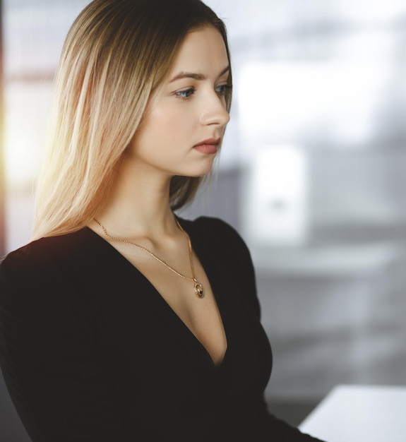 Jeune femme d'affaires travaillant dans un cabinet ensoleillé de son entreprise. Portrait d'entreprise ou portrait d'une secrétaire, assis au bureau dans un bureau.