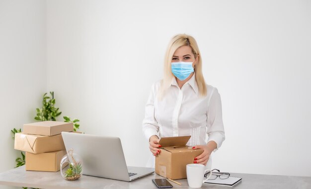 Jeune femme d'affaires travaillant à domicile, portant un masque de protection.