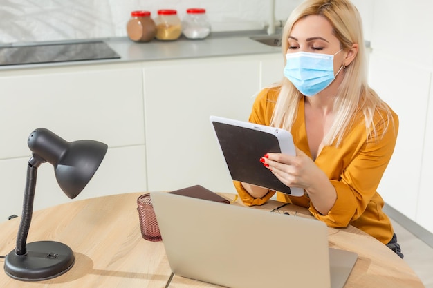 Jeune femme d'affaires travaillant à domicile, portant un masque de protection.