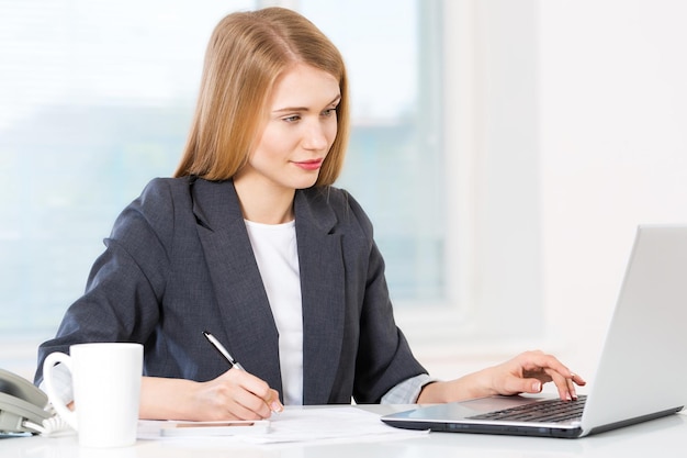 Jeune femme d'affaires travaillant avec un ordinateur portable et des documents au bureau