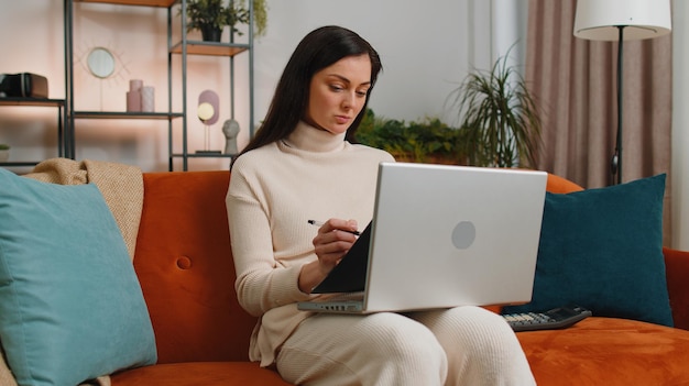 Jeune femme d'affaires travaillant avec un ordinateur portable et des documents planifiant le budget des dépenses à la maison