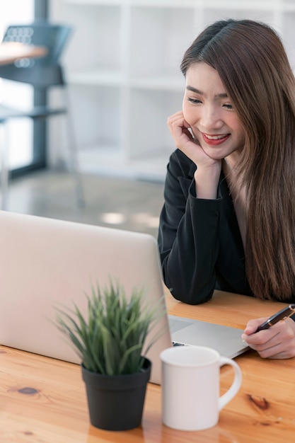 jeune femme d'affaires utilisant un ordinateur portable avec bonheur alors qu'elle était assise à son bureau, vue verticale.