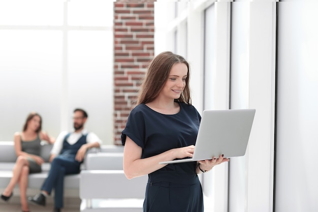 Jeune femme d'affaires utilise un ordinateur portable en se tenant au bureau .photo avec espace de copie