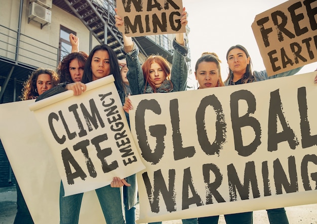 Jeune femme avec une affiche devant des personnes qui protestaient contre le changement climatique dans la rue. Rencontre sur les problèmes d'écologie, d'environnement, de réchauffement climatique, d'influence industrielle, d'urgence climatique.