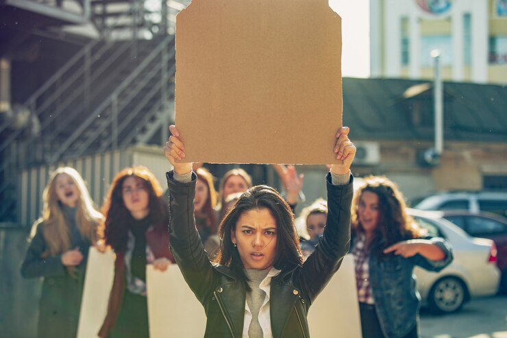Photo jeune femme avec une affiche vierge devant des personnes qui protestaient contre les droits des femmes et l'égalité dans la rue. réunion sur le problème au travail, la pression masculine, la violence domestique, le harcèlement. espace de copie.
