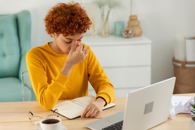 Une jeune femme africaine accablée souffrant du syndrome des yeux secs fatigue oculaire douleur masser le pont du nez Une fille stressée a besoin de repos après le travail Longue utilisation d'un ordinateur portable maux de tête mauvaise vision floue obtenir de mauvaises nouvelles