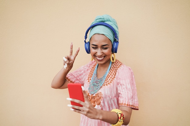 Jeune femme africaine à l'aide de l'application de téléphone mobile pour créer de la musique de liste de lecture