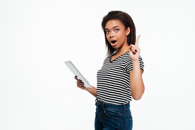 Jeune femme africaine à l'aide de la tablette tactile et avoir une idée.