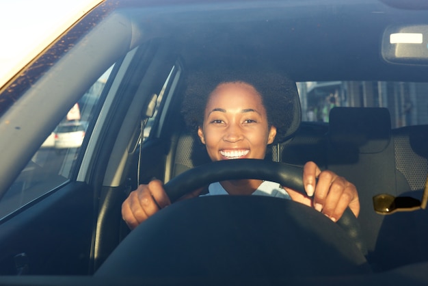 Jeune femme africaine au volant d&#39;une voiture et souriant