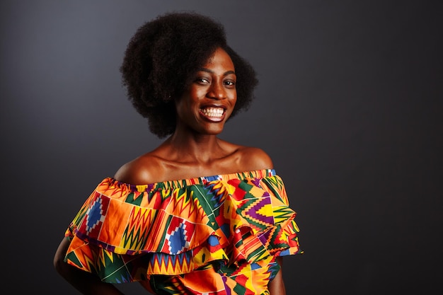 Jeune femme africaine de Côte d'Ivoire en vêtements traditionnels posant et souriant à la caméra