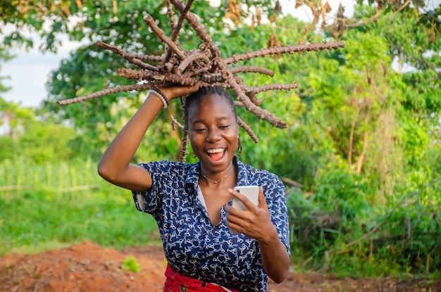 Photo jeune femme africaine dans une ferme souriant à l'aide de téléphone