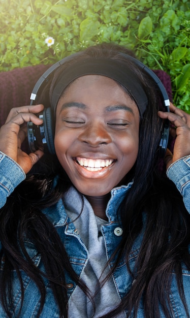 Jeune femme africaine écoutant de la musique se trouvant dans le parc.