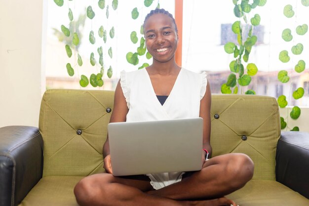 Photo une jeune femme africaine excitée célébrant son succès en regardant l'écran de son ordinateur portable.