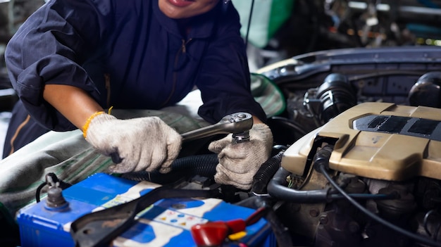 Jeune femme africaine mécanicienne automobile vérifiant et fixant le moteur de la voiture au garage de voiture de service Mécanicienne noire travaillant dans l'atelier de service et d'entretien automobile