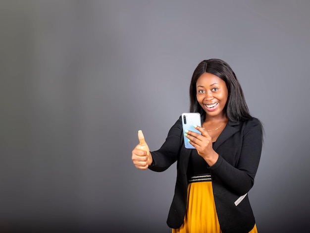 Jeune femme africaine noire tenant un téléphone portable donné un coup de pouce pour un accord