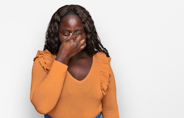 Jeune femme africaine portant des vêtements décontractés fatigué se frottant le nez et les yeux ressentant de la fatigue et des maux de tête. concept de stress et de frustration.