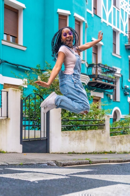 Une jeune femme africaine sautant dans une rue avec des maisons colorées