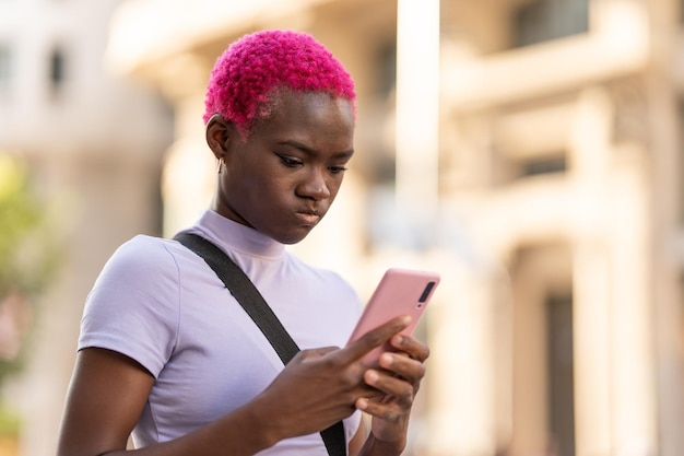 Jeune femme africaine sérieuse utilisant le mobile