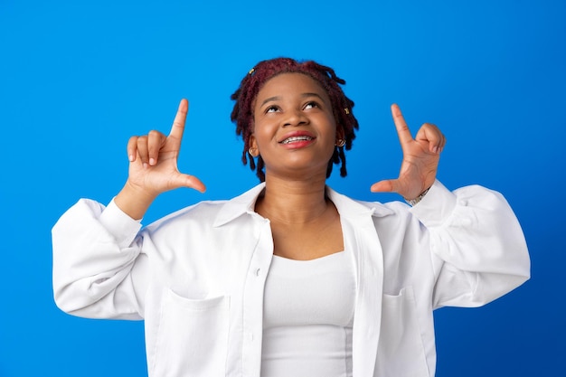 Jeune femme africaine souriante faisant un cadre avec les mains sur fond bleu