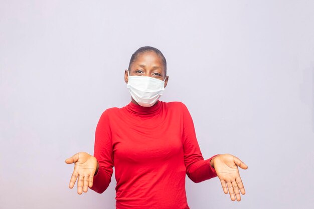 Jeune femme africaine souriante en masque levant les mains à la caméra